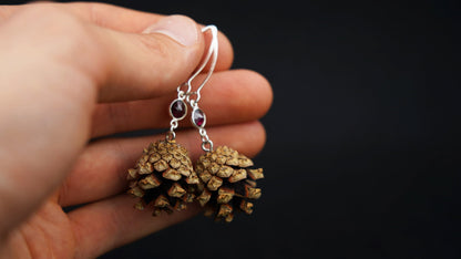 Kiefernzapfen-Ohrringe mit rotem Granat in 925 Silber in der Hand