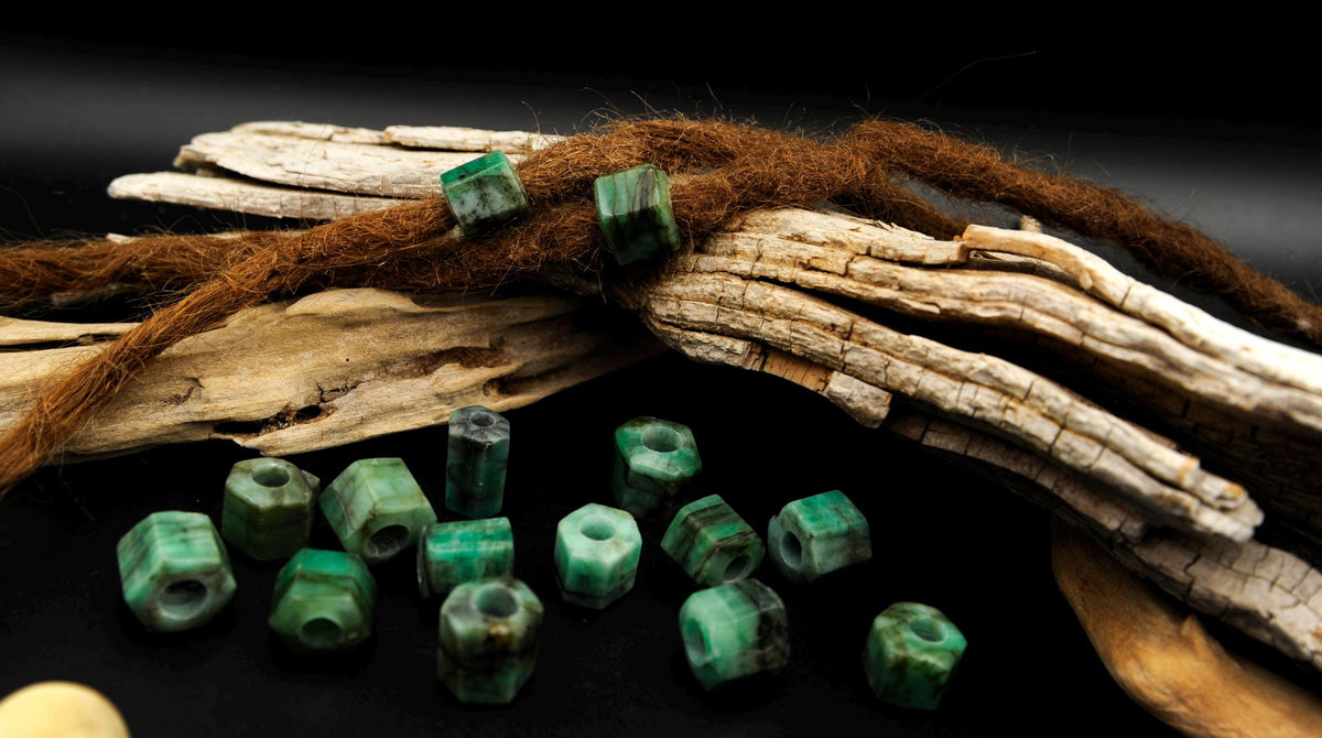 Grüne Smaragd-Dreadlockperlen an Dreads auf Treibholz